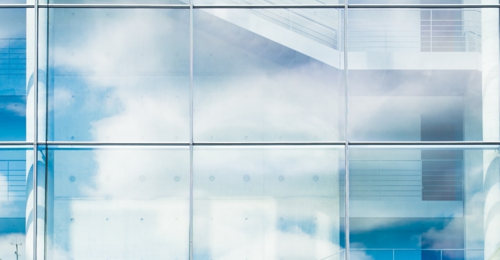 Reflection of the sky in the glass of a skyscraper showing an open staircase leading upwards.