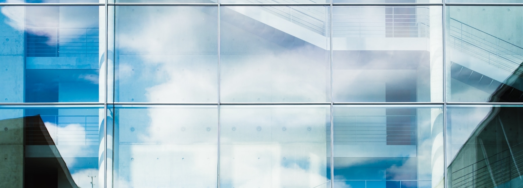 Reflection of the sky in the glass of a skyscraper showing an open staircase leading upwards.