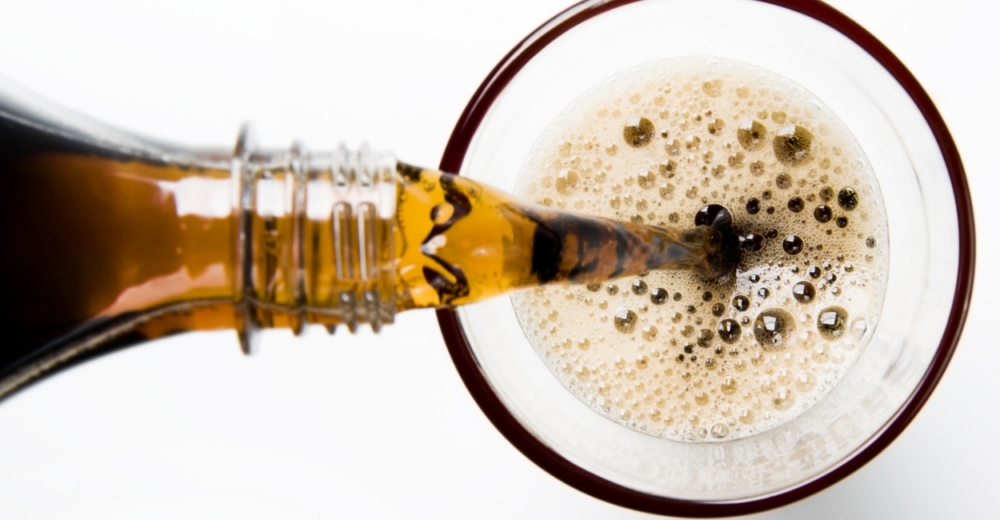 Pouring a glass of cola into a glass from a bottle