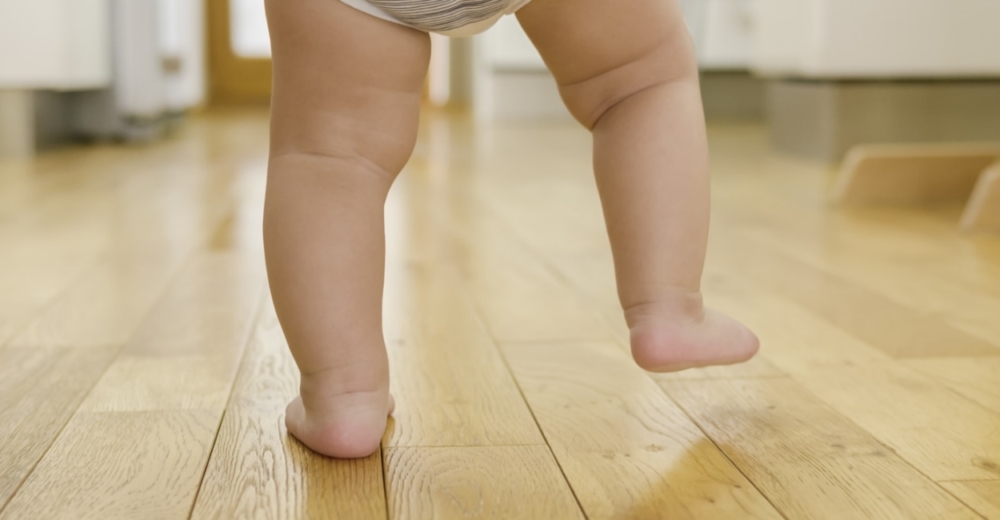 Baby feet walking on wooden floor