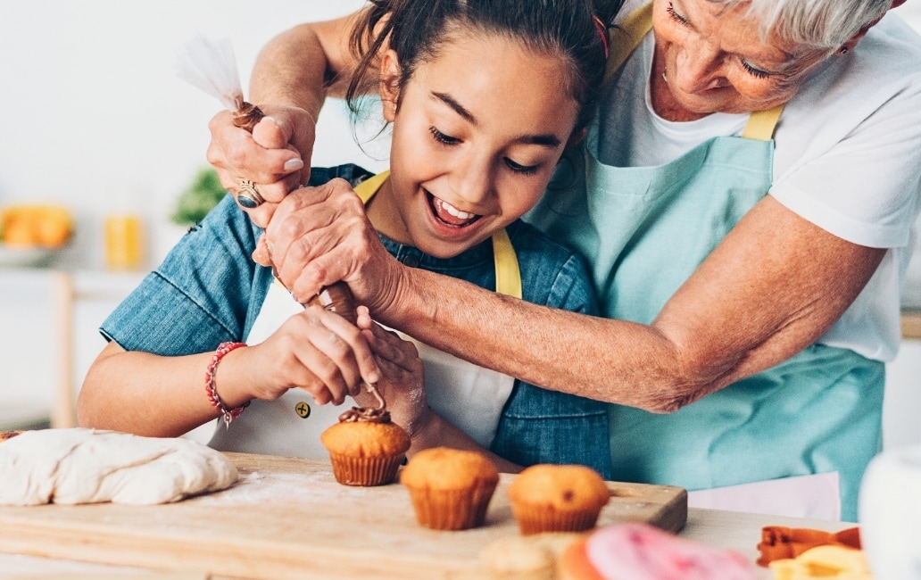 A woman with a girl decorating cupcakes