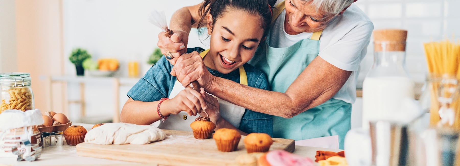 A woman with a girl decorating cupcakes