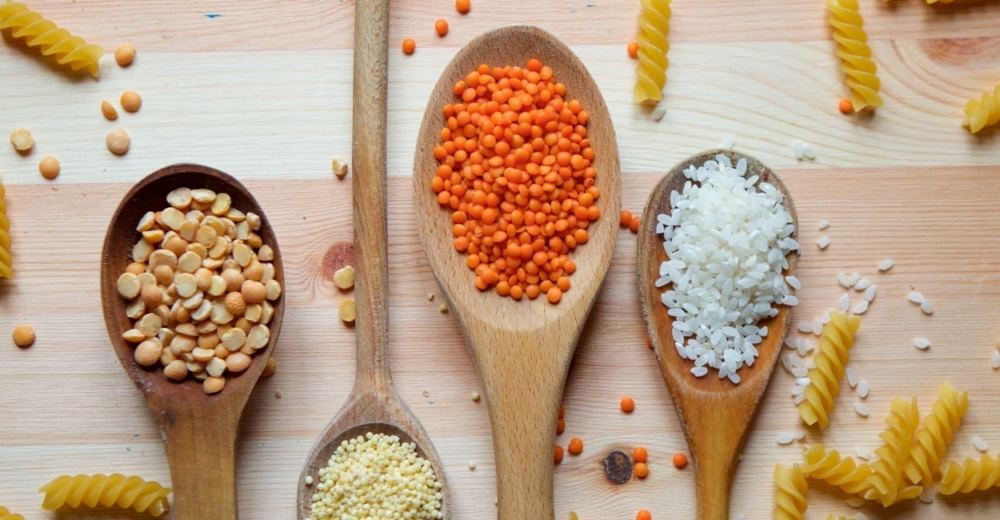 Various wooden spoons with pulses, pasta, rice and other foods