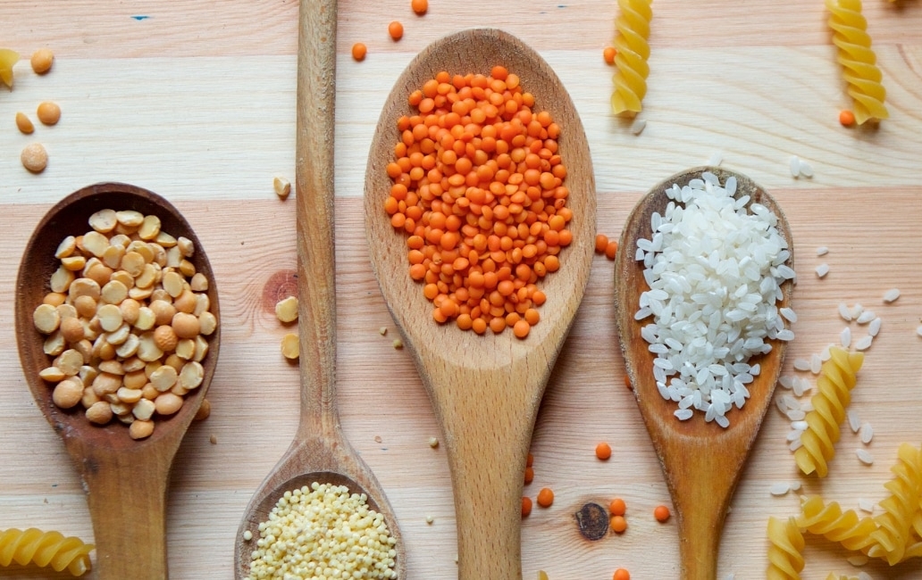 Various wooden spoons with pulses, pasta, rice and other foods