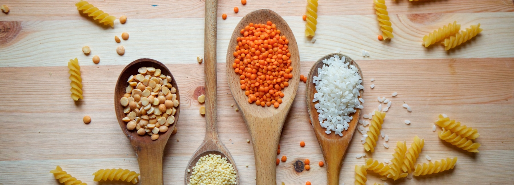 Various wooden spoons with pulses, pasta, rice and other foods