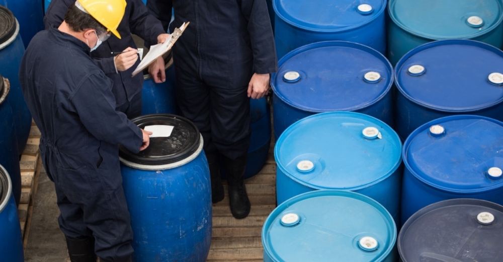 Employees with drums of chemicals checking data