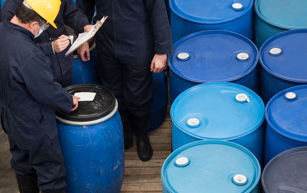 Employees with drums of chemicals checking data