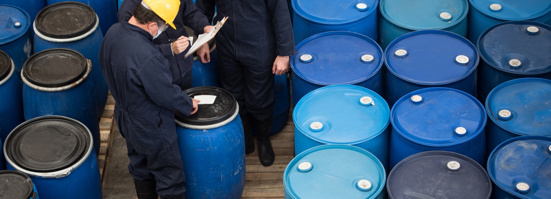 Employees with drums of chemicals checking data