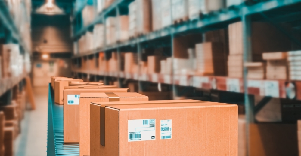 Warehouse with shelves with stored products and an aisle with cardboard boxes