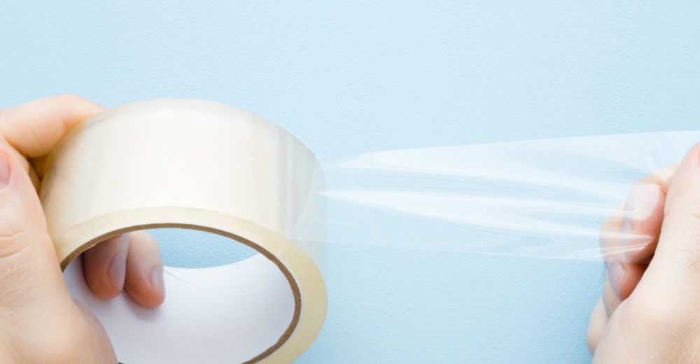 Person holding a strip of transparent adhesive tape