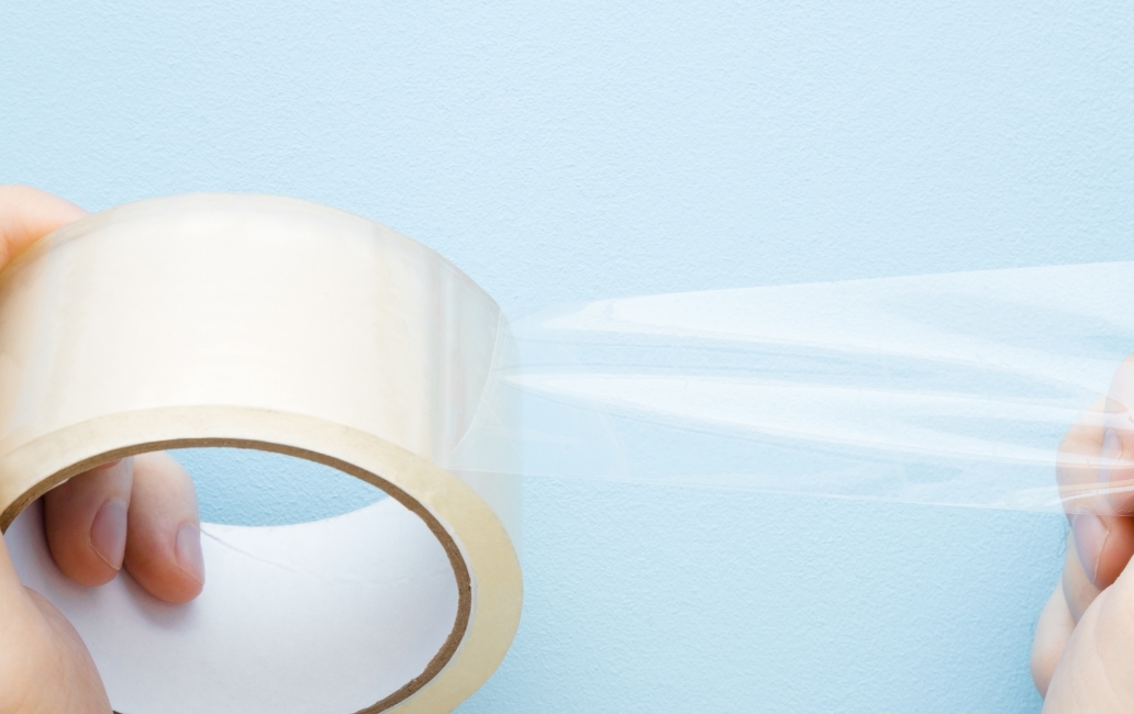 Person holding a strip of transparent adhesive tape