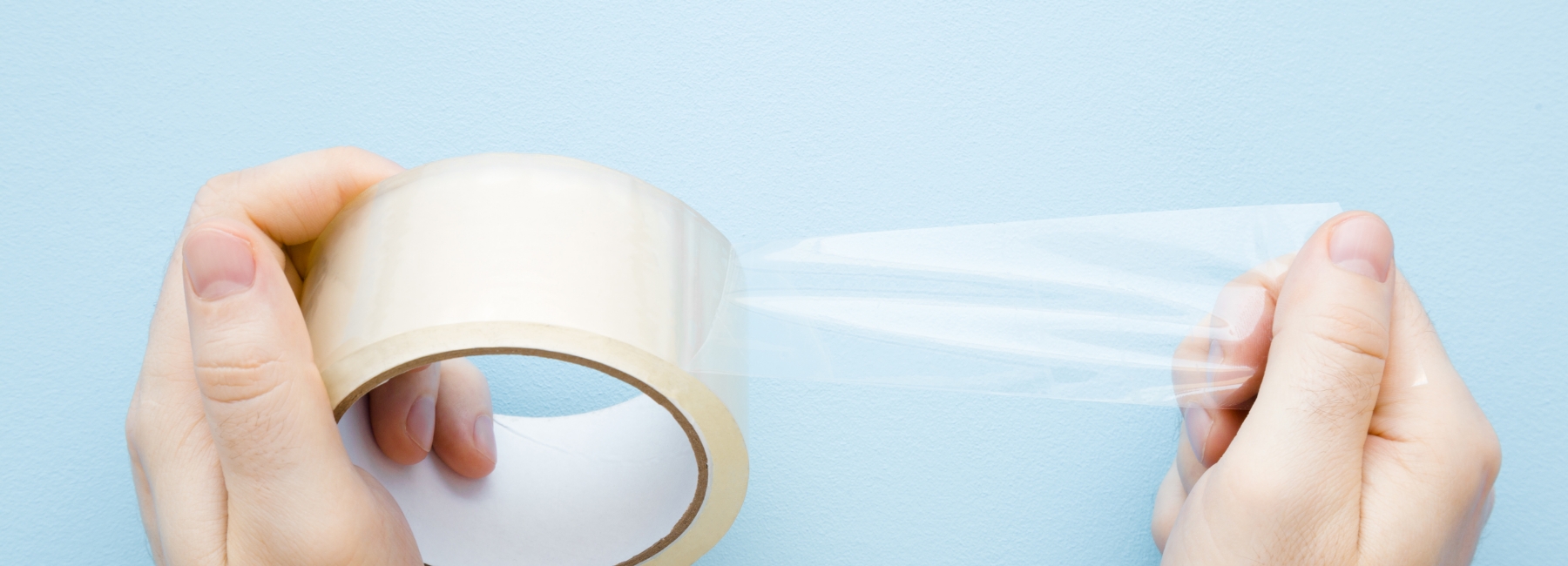 Person holding a strip of transparent adhesive tape